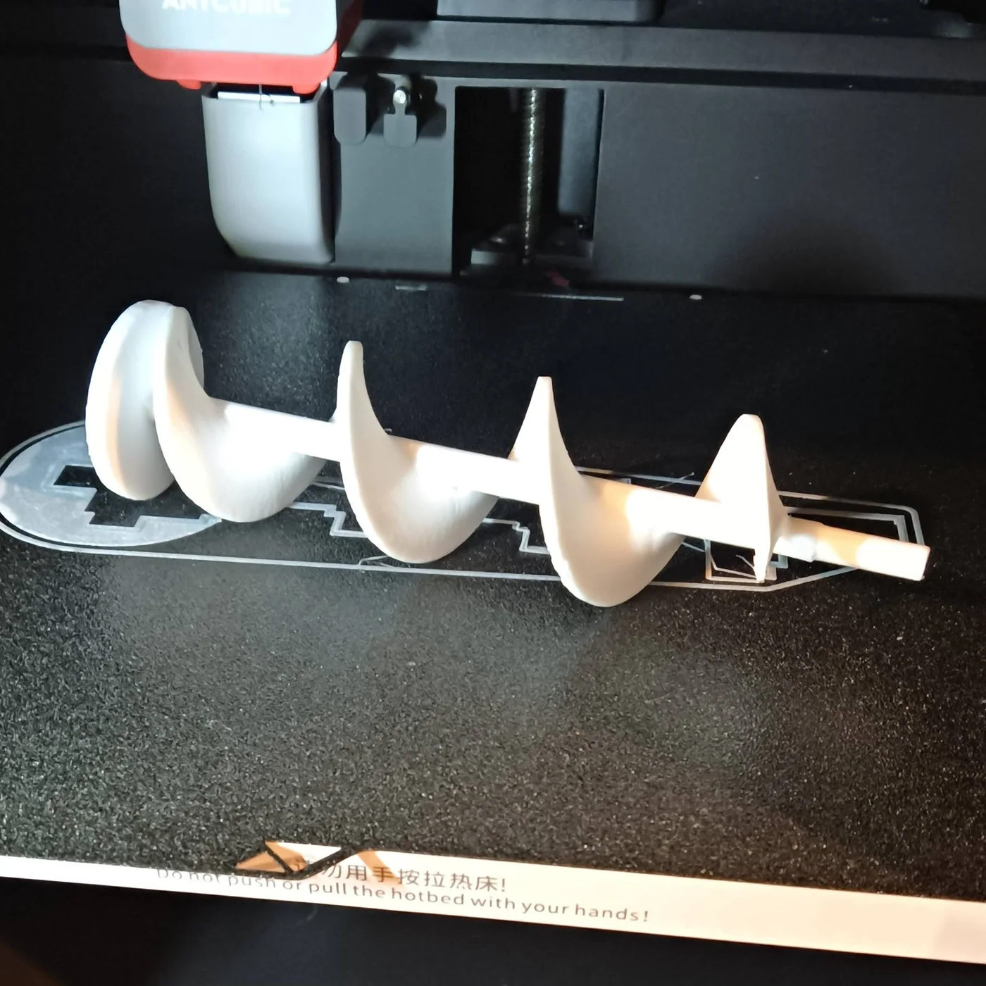 White 3D-printed auger on a printer build plate