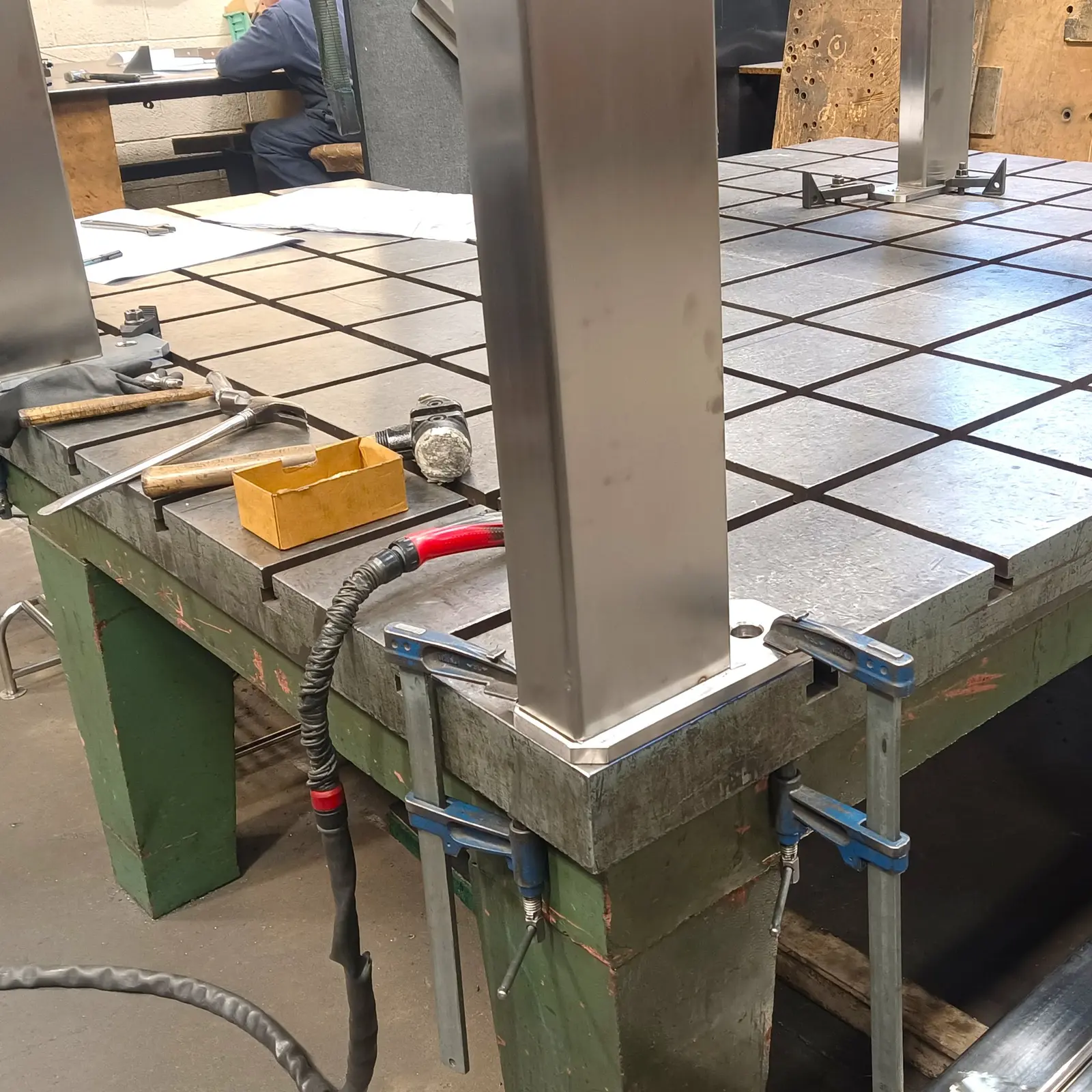 Large fabricated metal frames aligned on a welding table